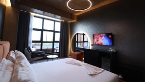 A hotel room with a large bed, a desk, a TV, and a view of the outdoors. - Toka Hotel Restaurant (Udënisht)