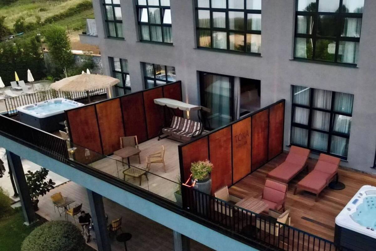 Une terrasse sur le toit équipée d’un jacuzzi, de chaises longues et d’un espace salon avec une table et des chaises.