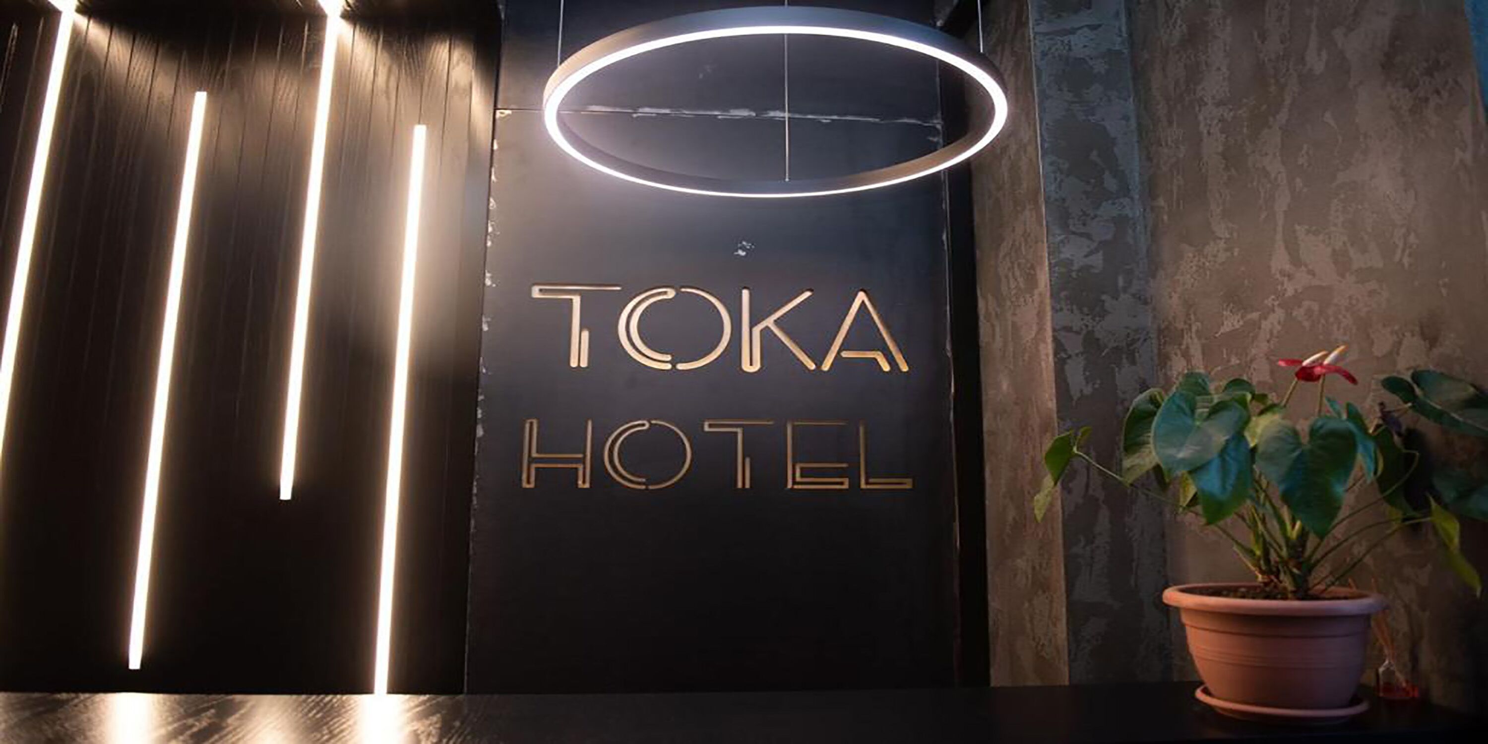 A Toka Hotel sign with a modern design, featuring illuminated letters and a circular light above.