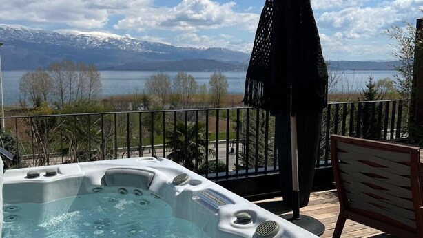 A hot tub on a deck with a view of mountains and a lake. - Toka Hotel Restaurant (Udënisht)
