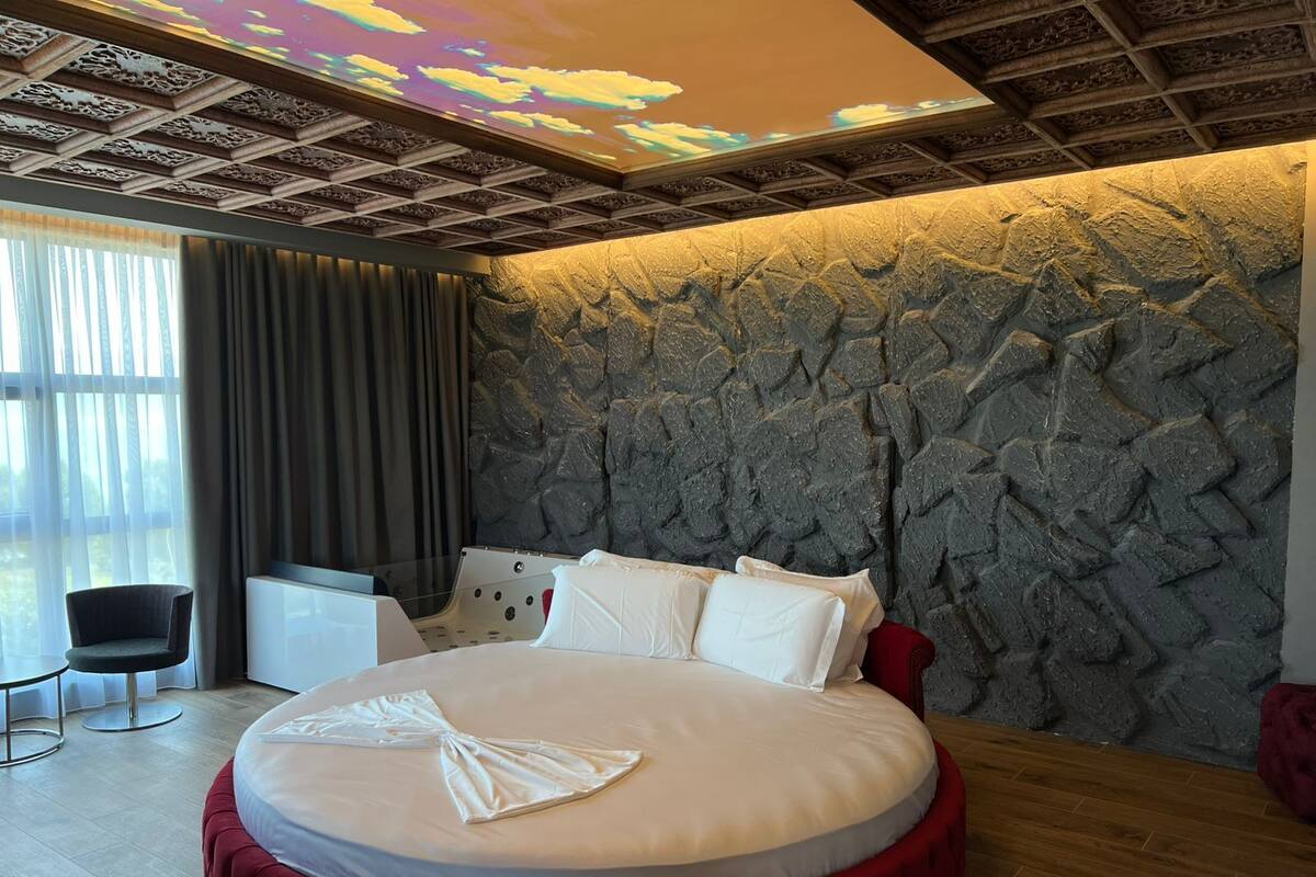Une chambre d’hôtel moderne avec un lit rond, un bureau et une grande fenêtre.