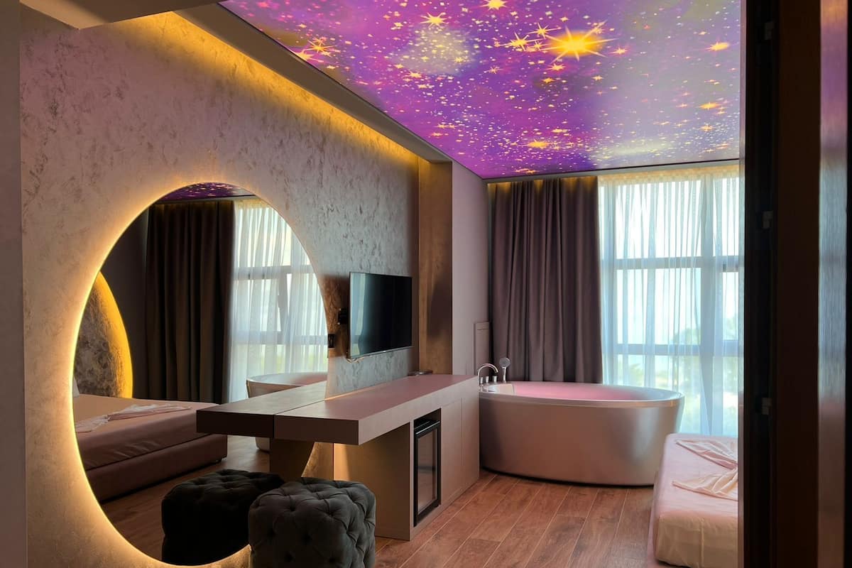 Une salle de bain moderne avec un plafond étoilé, un grand miroir, une baignoire et un meuble-lavabo.