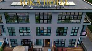 A modern hotel with a rooftop terrace featuring hot tubs, seating areas, and a large umbrella. - Toka Hotel Restaurant (Udënisht)