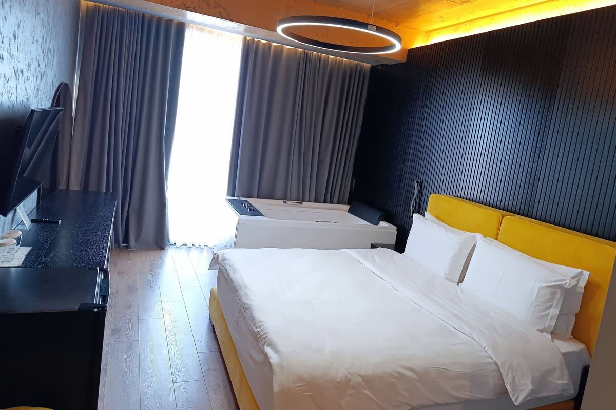 Une chambre d’hôtel avec un lit, un bureau et une télévision.