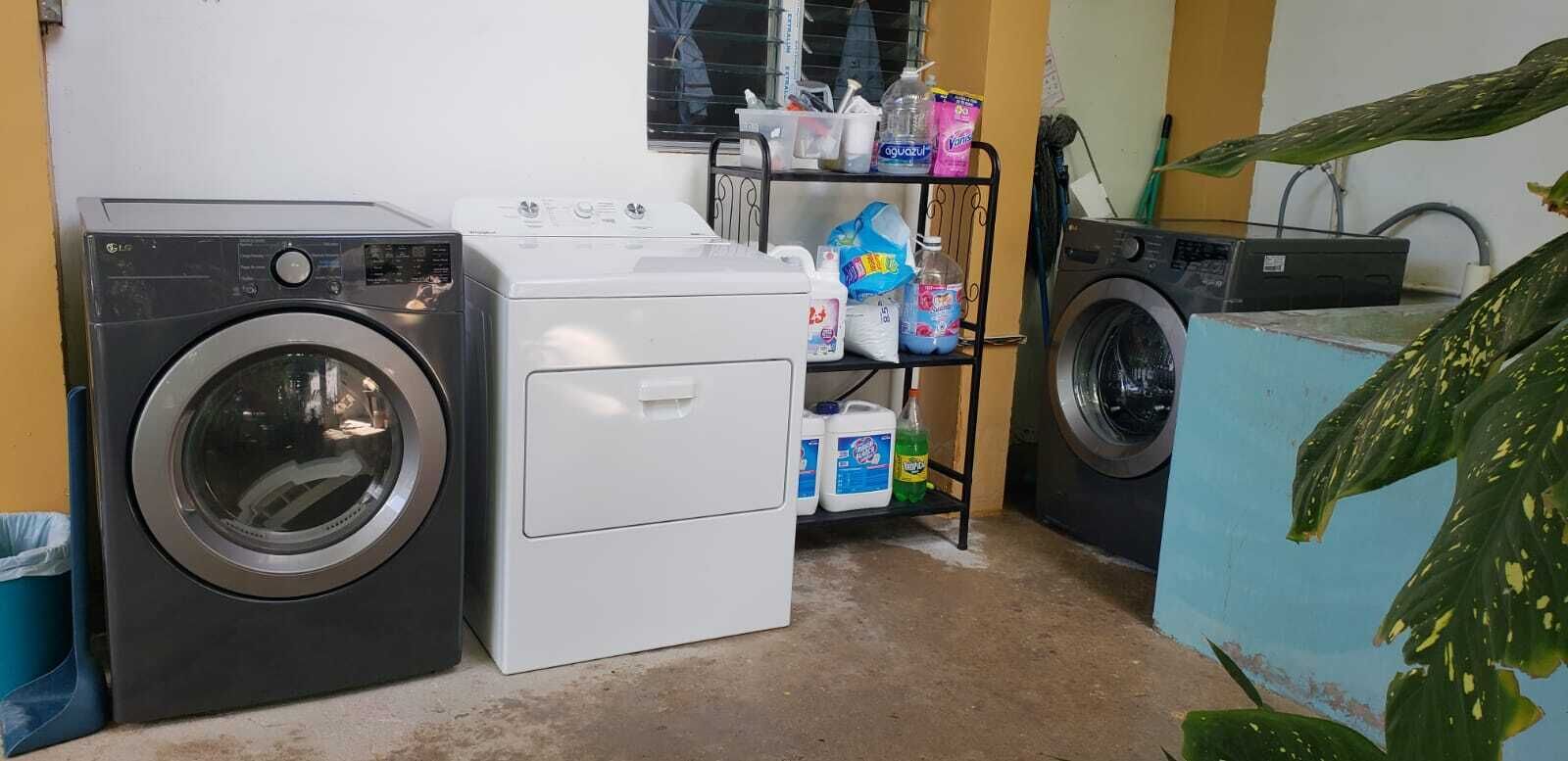 A laundry area with a front-loading washer, a top-loading dryer, and a shelf with cleaning supplies.