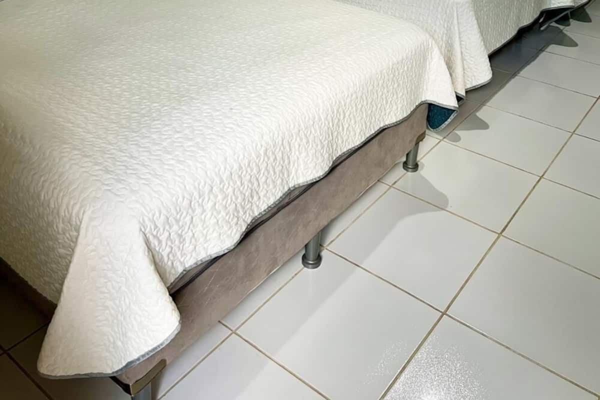 A room with two beds, each with a white quilted bedspread and pillows.