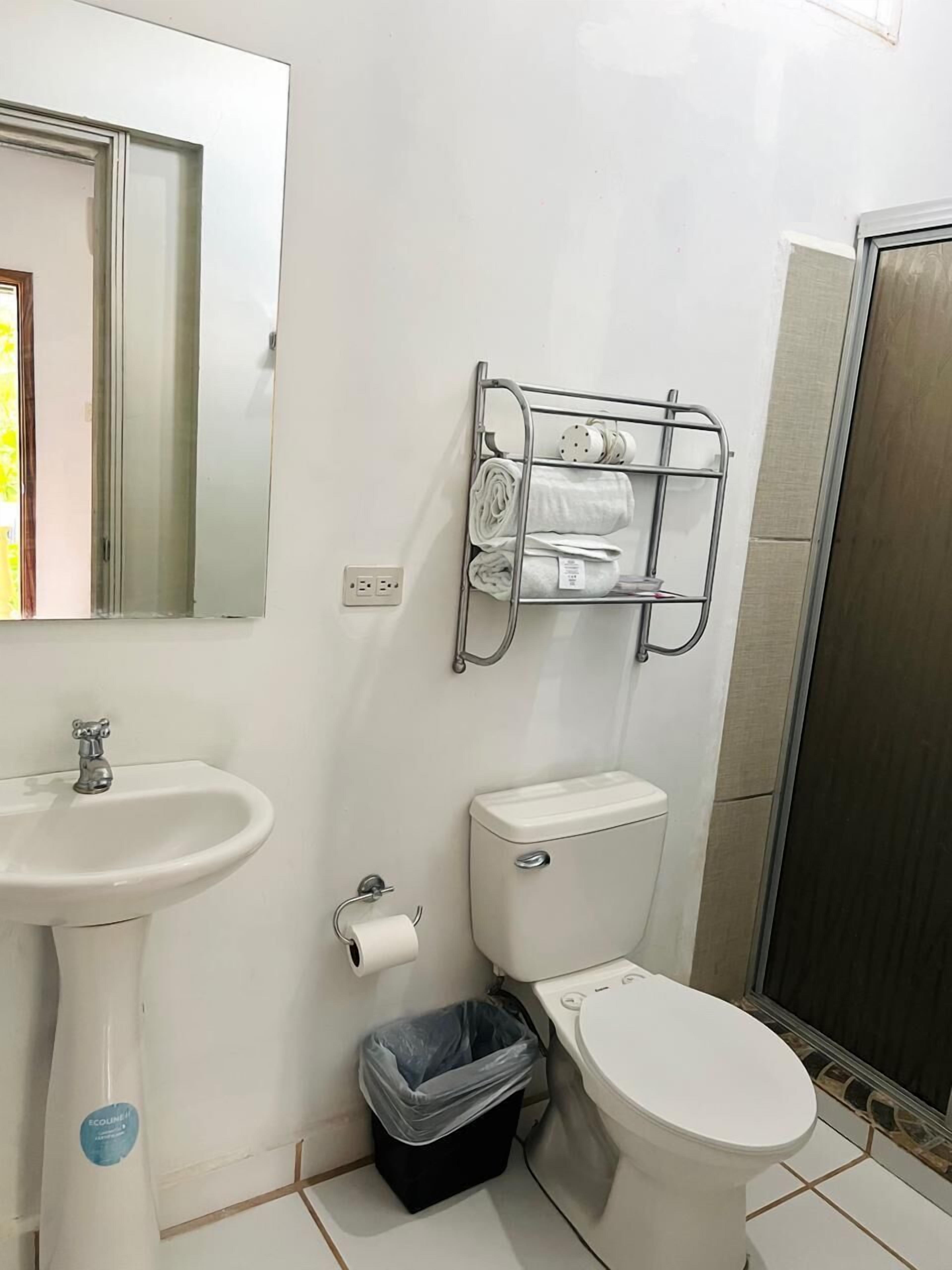 Une salle de bain avec un lavabo blanc, des toilettes et un porte-serviettes en métal.
