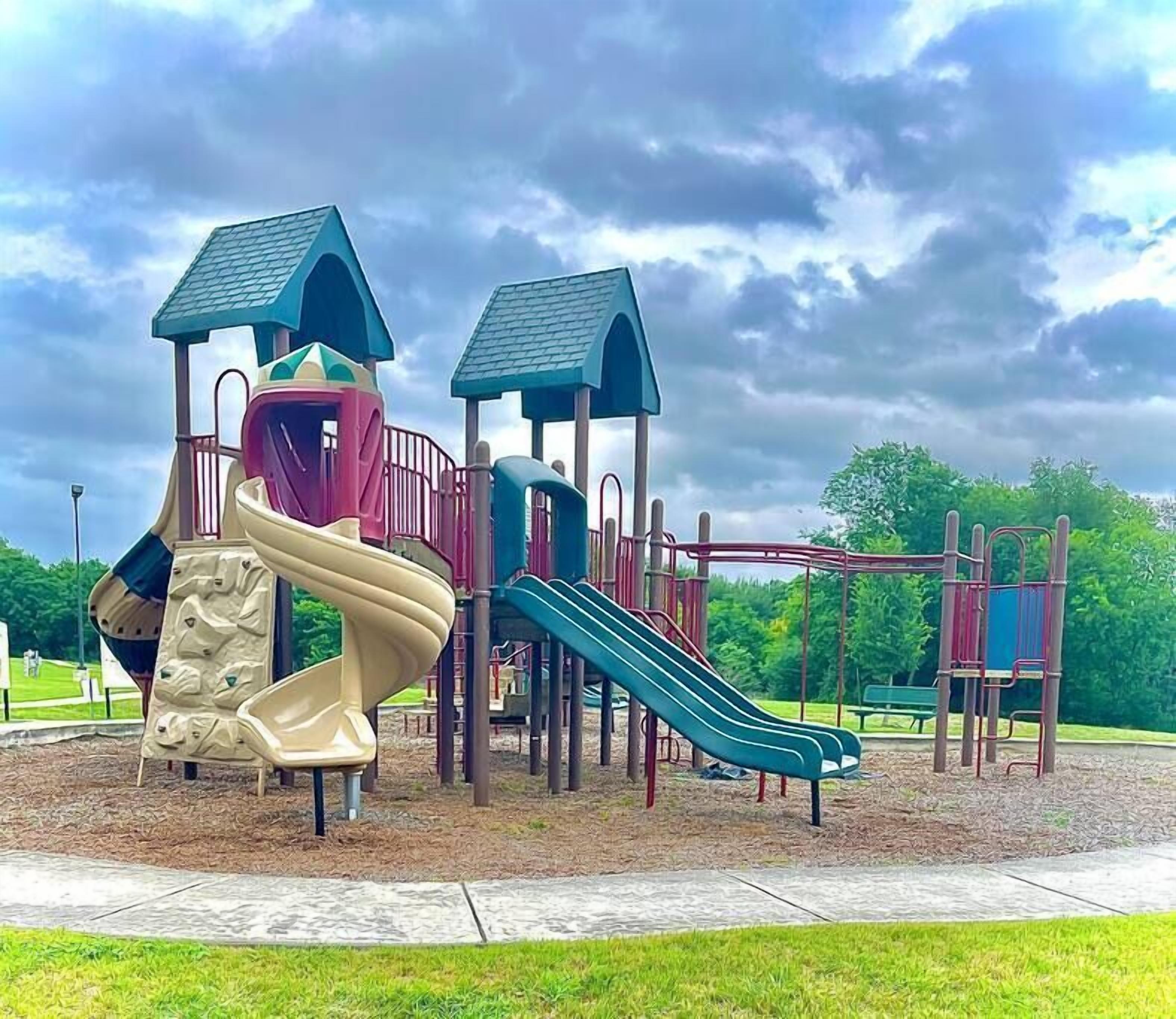 Ein Spielplatz mit Rutsche, Kletterwand und verschiedenen Spielgeräten.