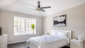 A bedroom with a bed, a nightstand, a ceiling fan, a window with blinds, and a wall-mounted artwork. - Private & Clean Retreat Near Lackland AFB | Pet-Friendly & Family Ready! (San Antonio)