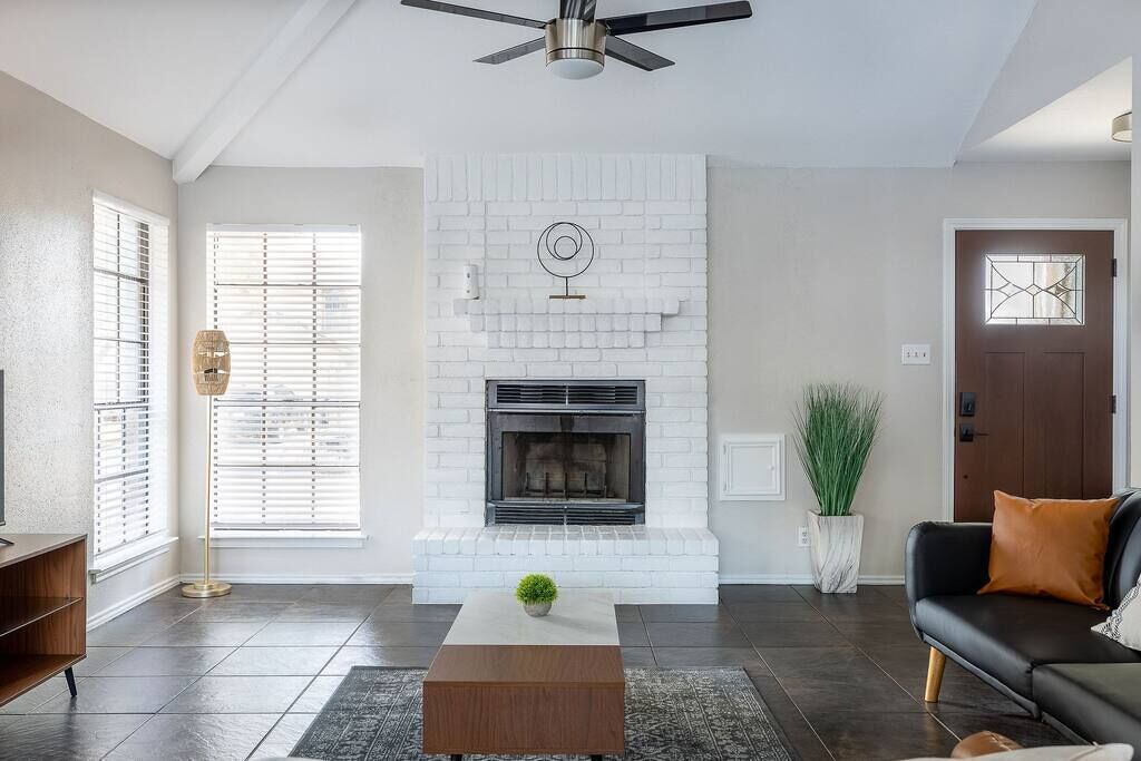 Un salon doté d’une cheminée, d’un ventilateur de plafond et d’une porte avec une fenêtre.