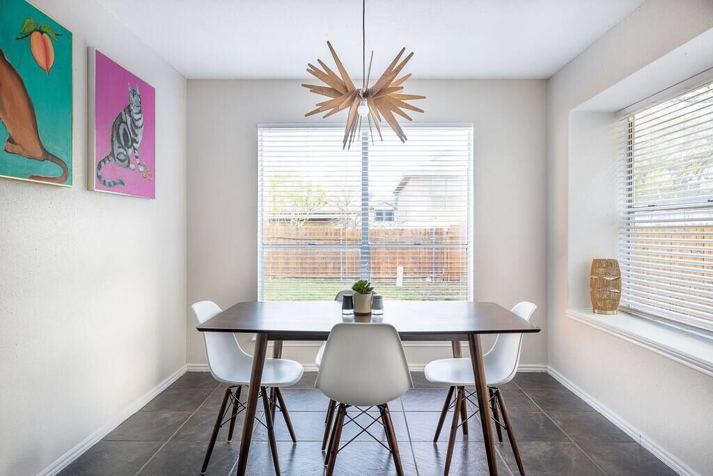 A dining area with a table, chairs, a pendant light, and artwork on the wall.