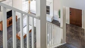 A spacious living area with a staircase, a television, and a ceiling fan. - Private & Clean Retreat Near Lackland AFB | Pet-Friendly & Family Ready! (San Antonio)