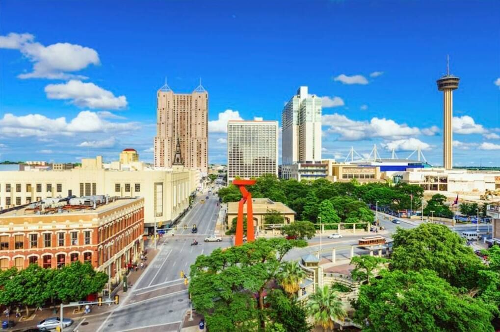 A cityscape with a prominent tower, a tall building, and a red sculpture.