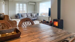 Una sala de estar acogedora con una mesa de madera, sillas de mimbre, un sofá con cojines y una estufa de leña.
