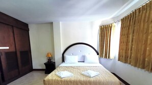 A hotel room with a bed, a nightstand, a lamp, and a wardrobe. - Kata Place Hotel (Karon)