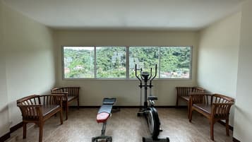 Una habitación con una banca, una bicicleta estática y vistas a un paisaje verde a través de amplias ventanas.