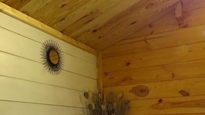 A wooden cabin interior with a white dresser, a sunburst mirror, and a vase with dried flowers. - Les Gîtes de Petrocoriis (Boulazac-Isle-Manoire)