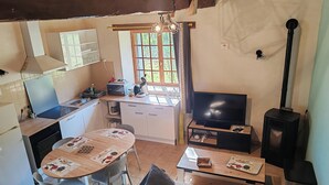 A compact kitchen with a dining area, a sofa, and a television. - Les Gîtes de Petrocoriis (Boulazac-Isle-Manoire)