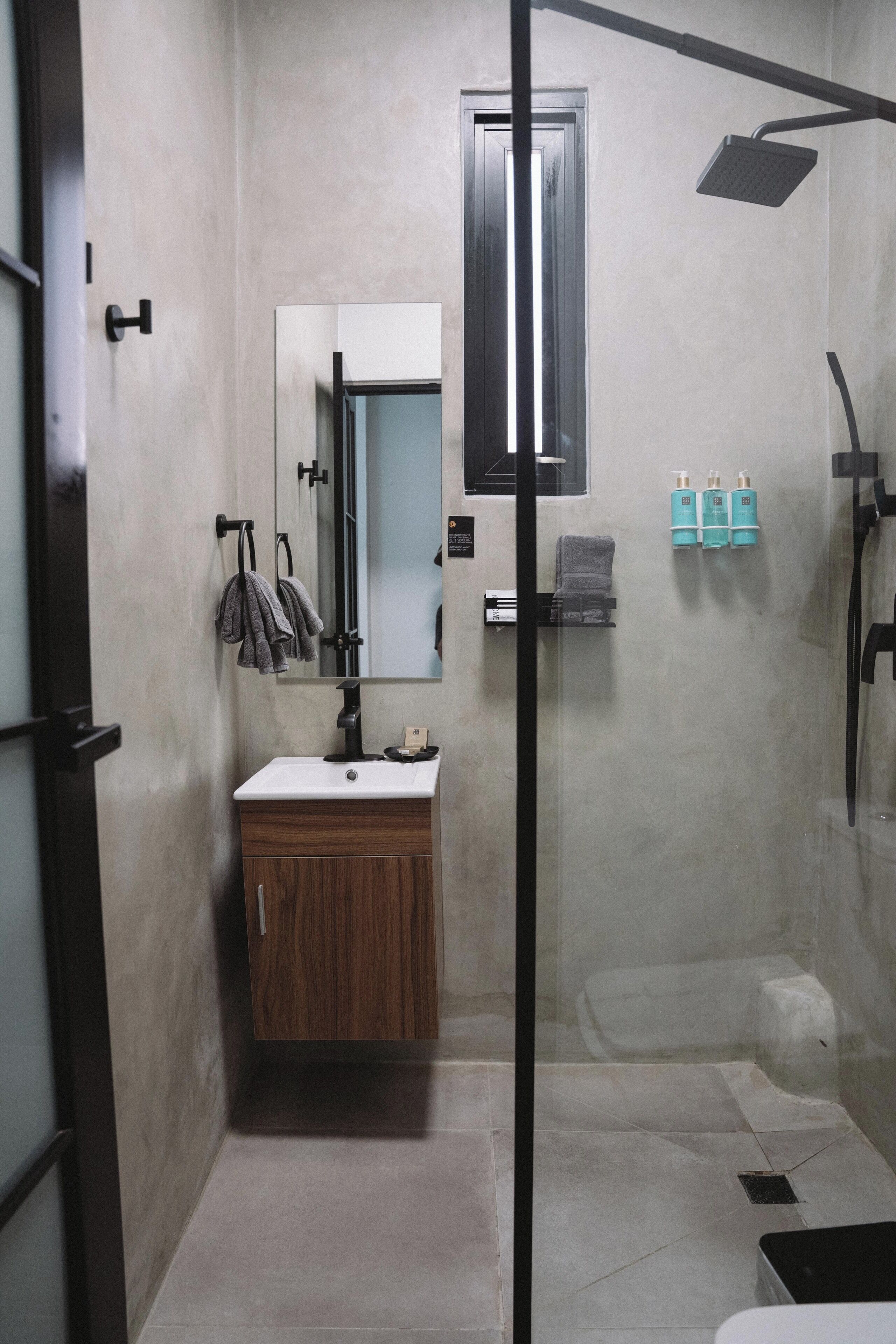 A modern bathroom with a glass shower enclosure, a wooden vanity, and a mirror above the sink.