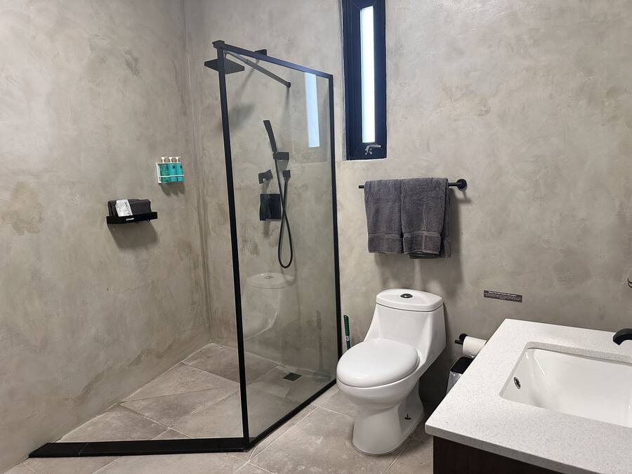 Un baño moderno con ducha de vidrio, inodoro y lavamanos.