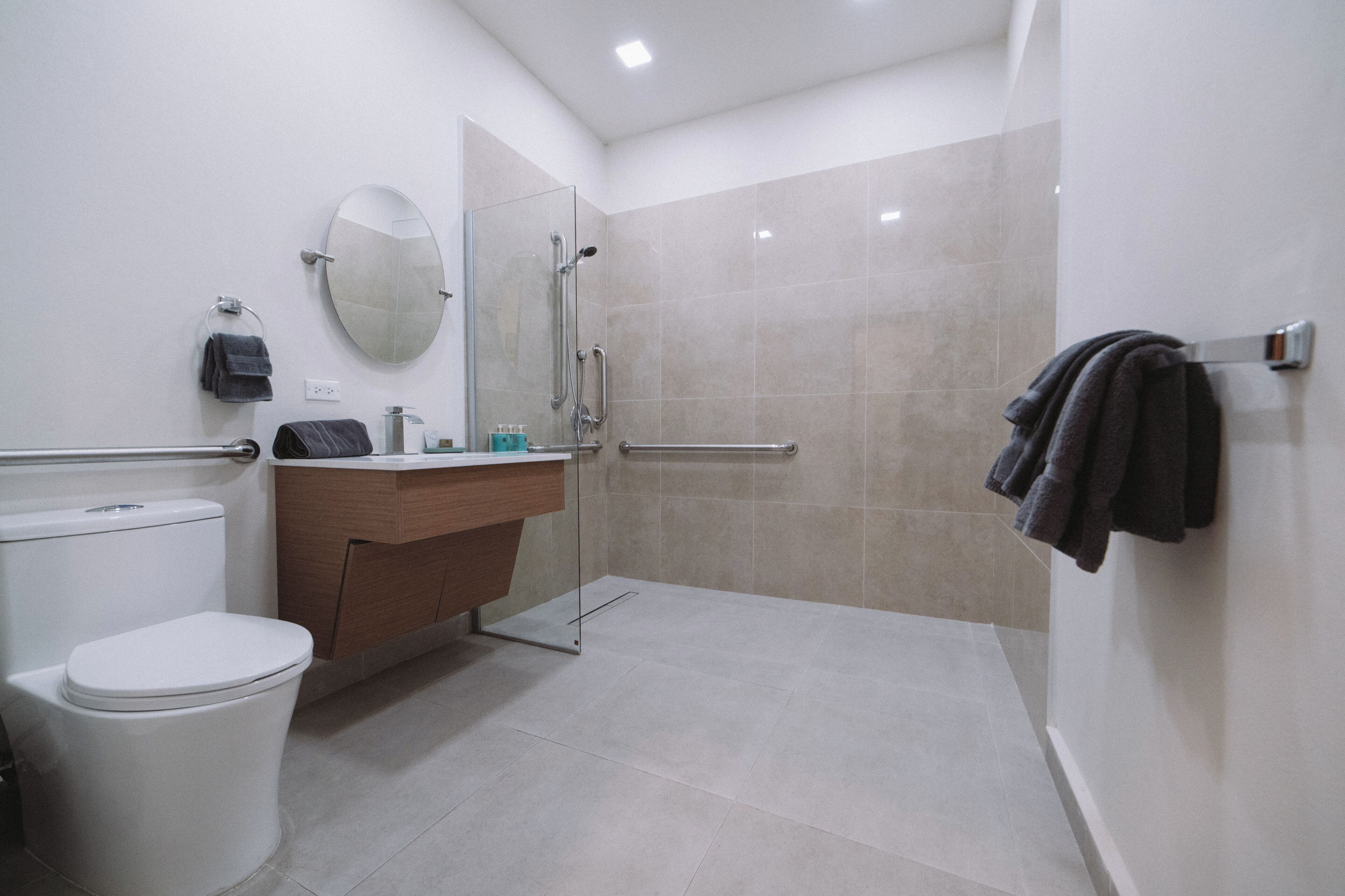 A modern bathroom with a toilet, sink, mirror, and shower.