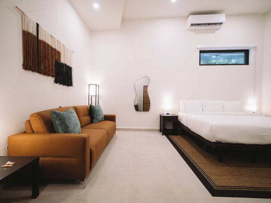 Una camera da letto moderna con un divano, un letto, un comodino, una lampada e un'opera d'arte appesa al muro.