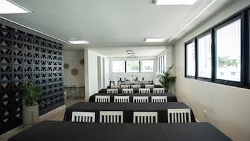 A conference room with multiple tables and chairs, large windows, and a decorative wall.
