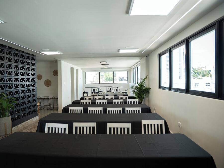 A conference room with multiple tables and chairs, large windows, and a decorative wall.