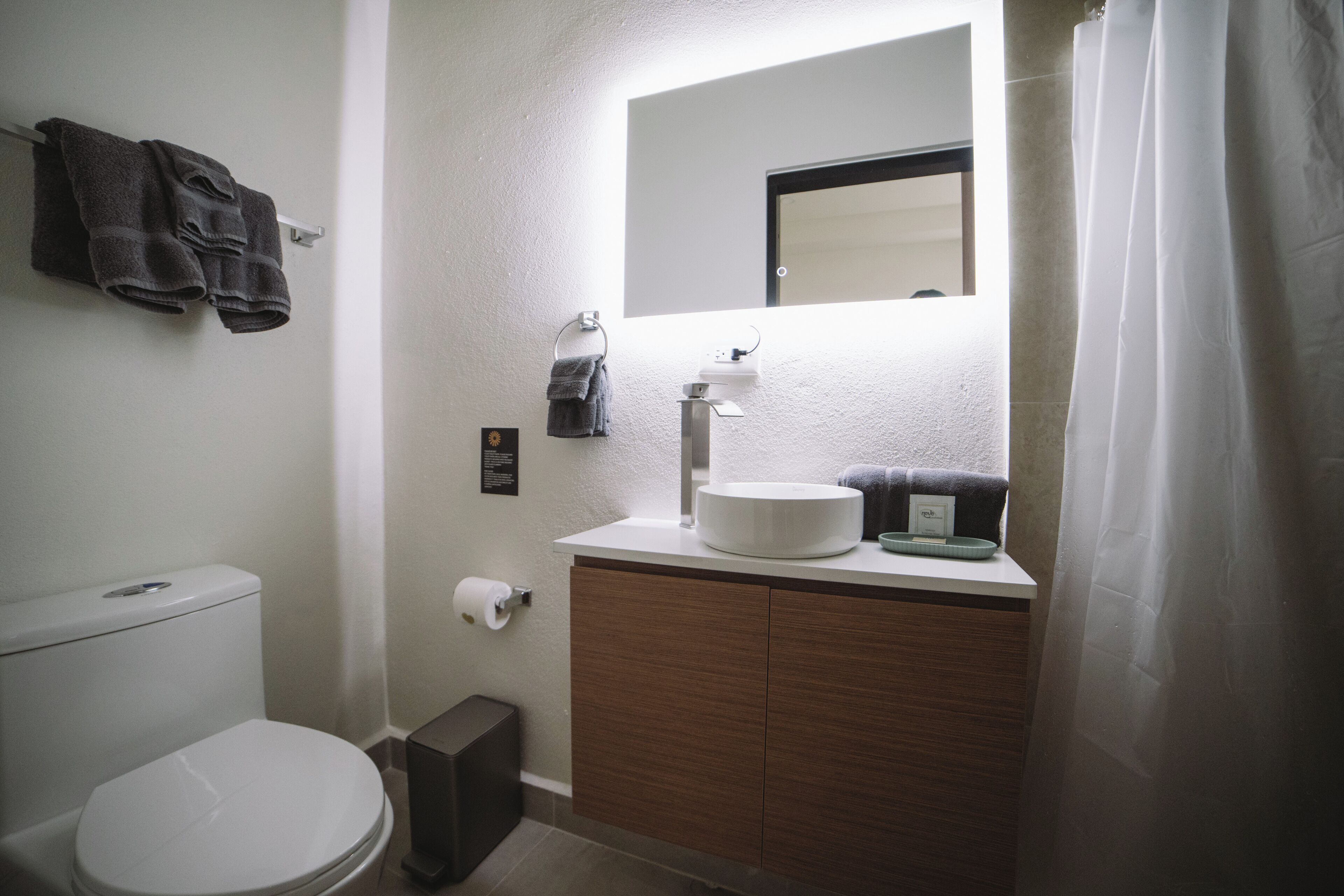 Un baño moderno con inodoro, lavamanos y espejo.