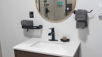 A bathroom with a white sink, dark wooden vanity, a round mirror, and a towel rack.