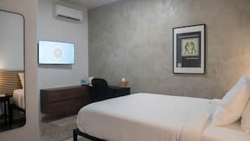 A bedroom with a bed, a dresser, a bedside table, a mirror, and a framed picture on the wall.
