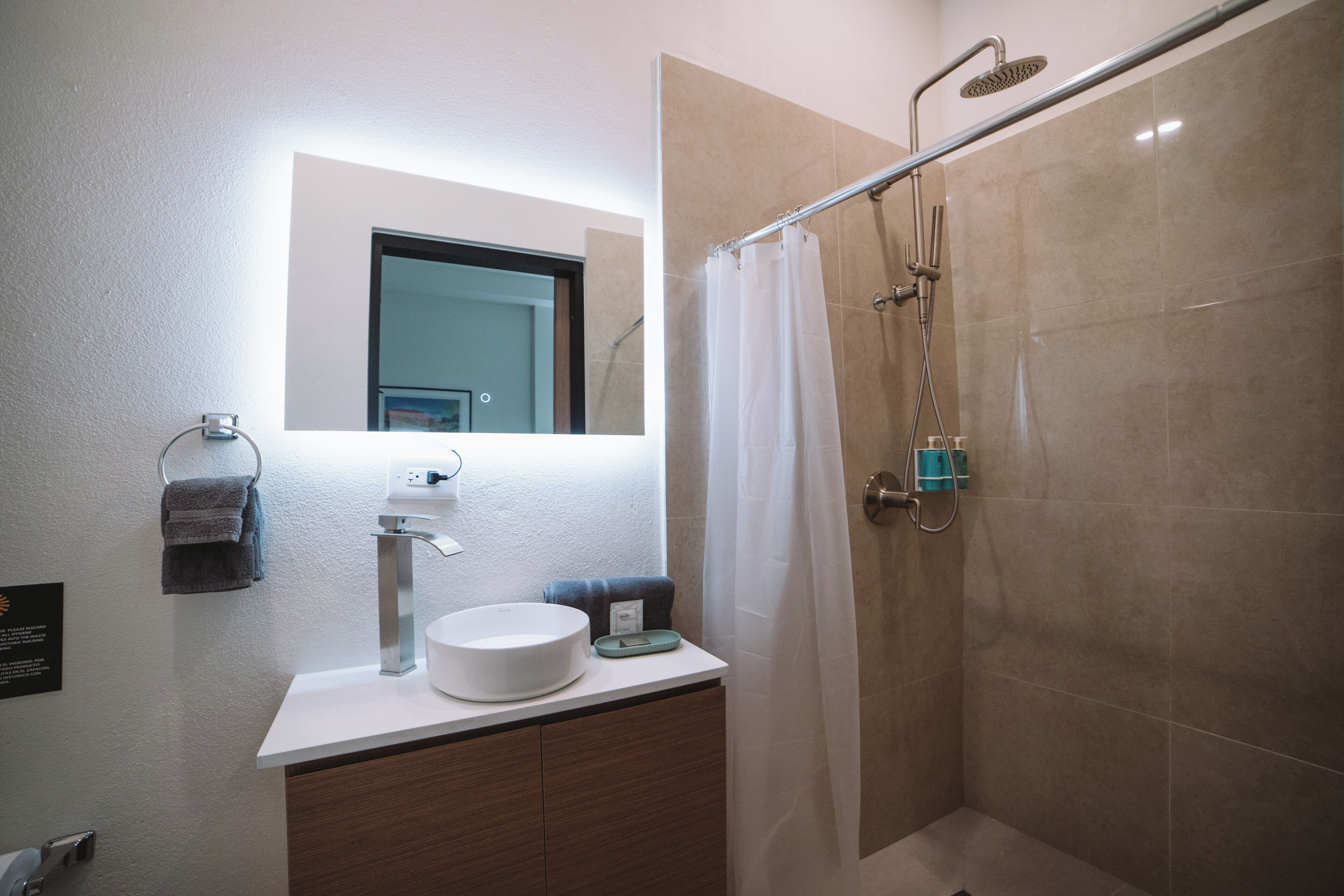 A modern bathroom with a sink, mirror, and shower.