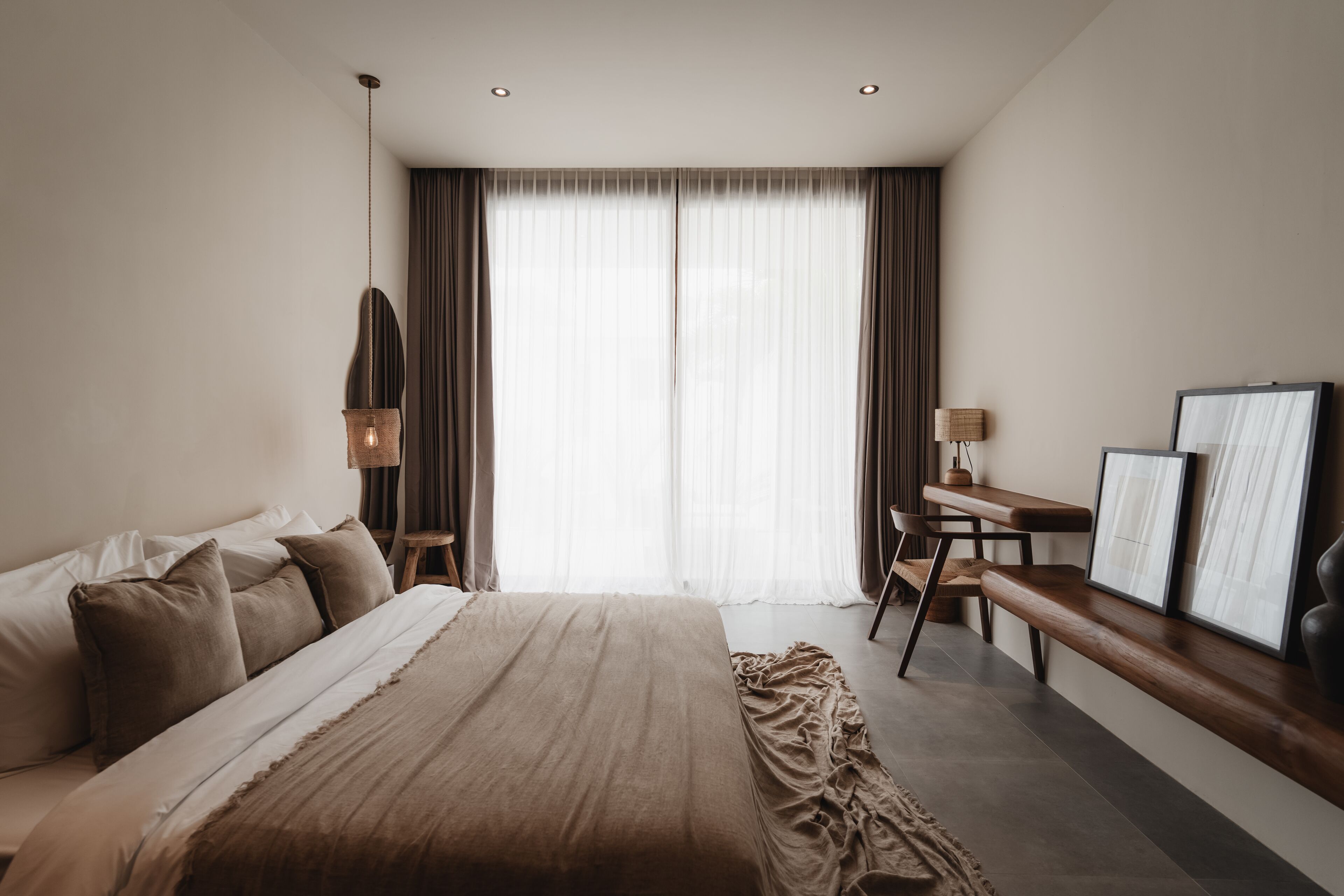 A modern hotel room with a large bed, a desk, and a bench.