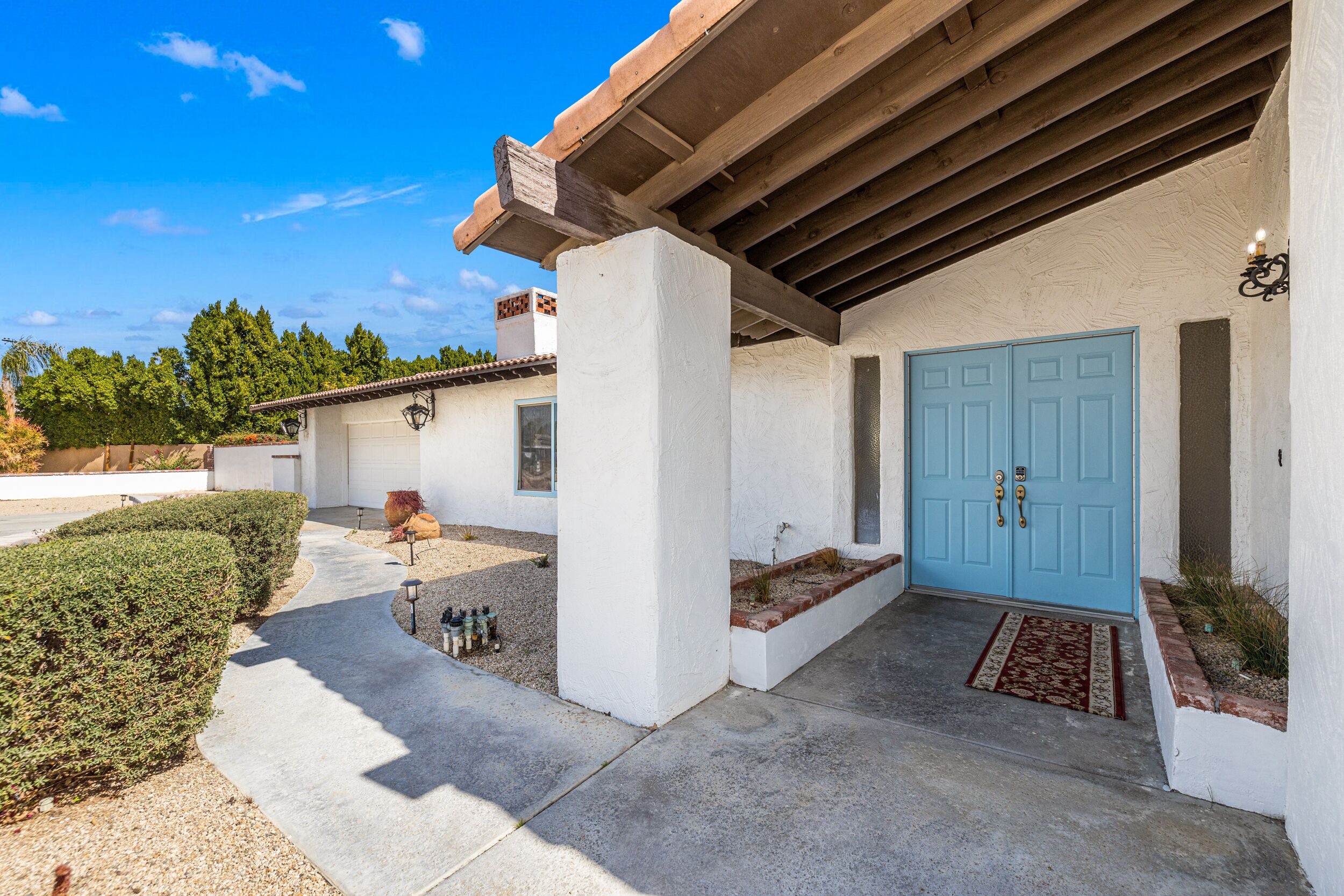 A modern house with a blue door, white exterior walls, and a concrete patio.