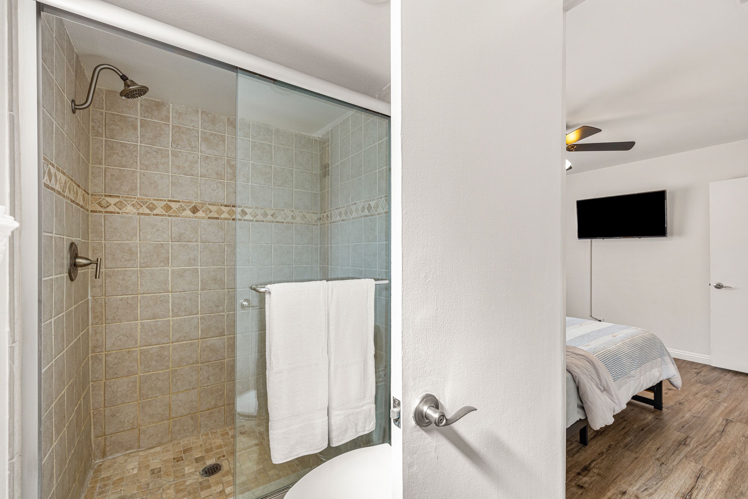 Un bany amb un box de dutxa de vidre, un lavabo blanc i un vàter.