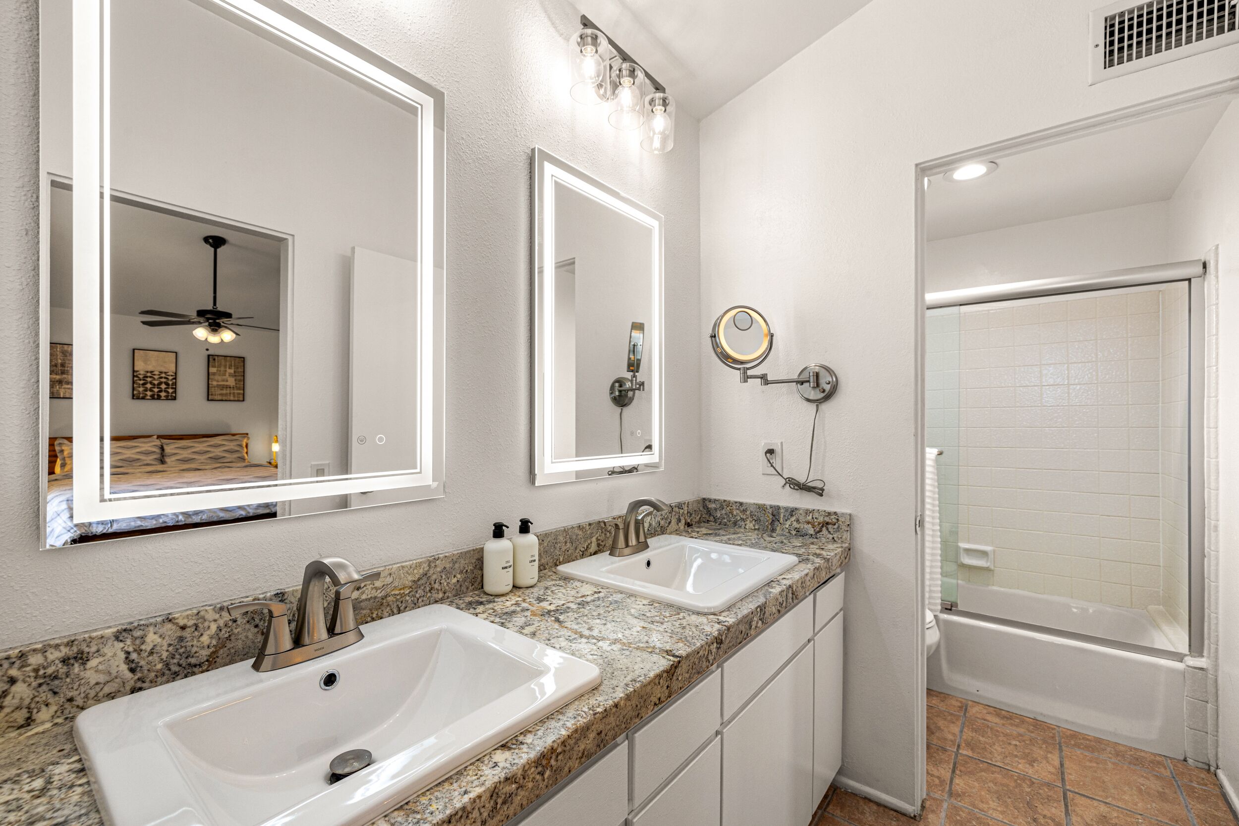 A bathroom with two sinks, a mirror, and a shower.