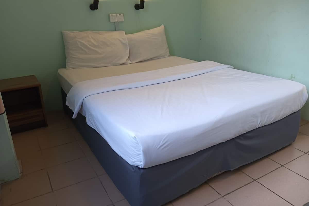 A single-bed room with a bed, a nightstand, and a wall-mounted light fixture.