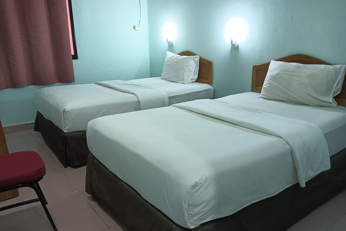 A hotel room with two beds, a red chair, and wall-mounted lights.