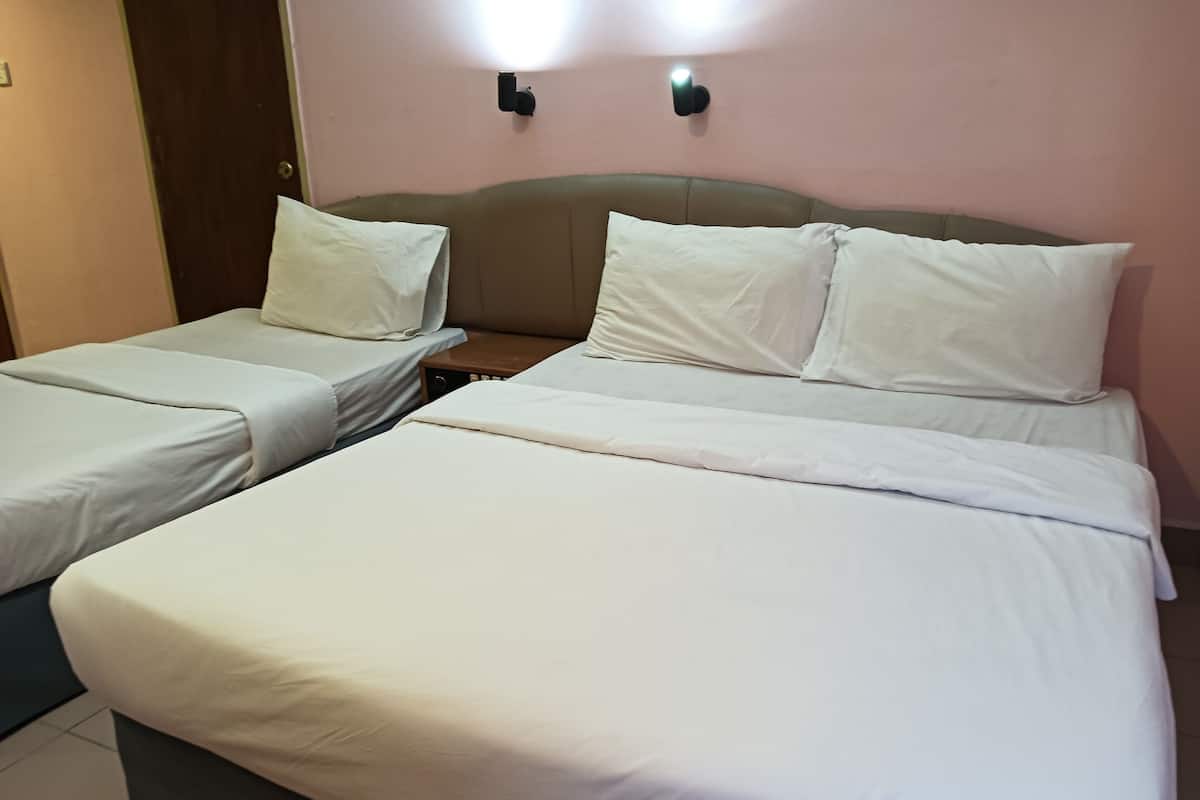 A hotel room with two single beds and one double bed, all with white linens.