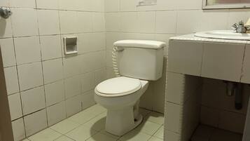 A small, clean bathroom with a toilet, sink, and a notice on the wall.