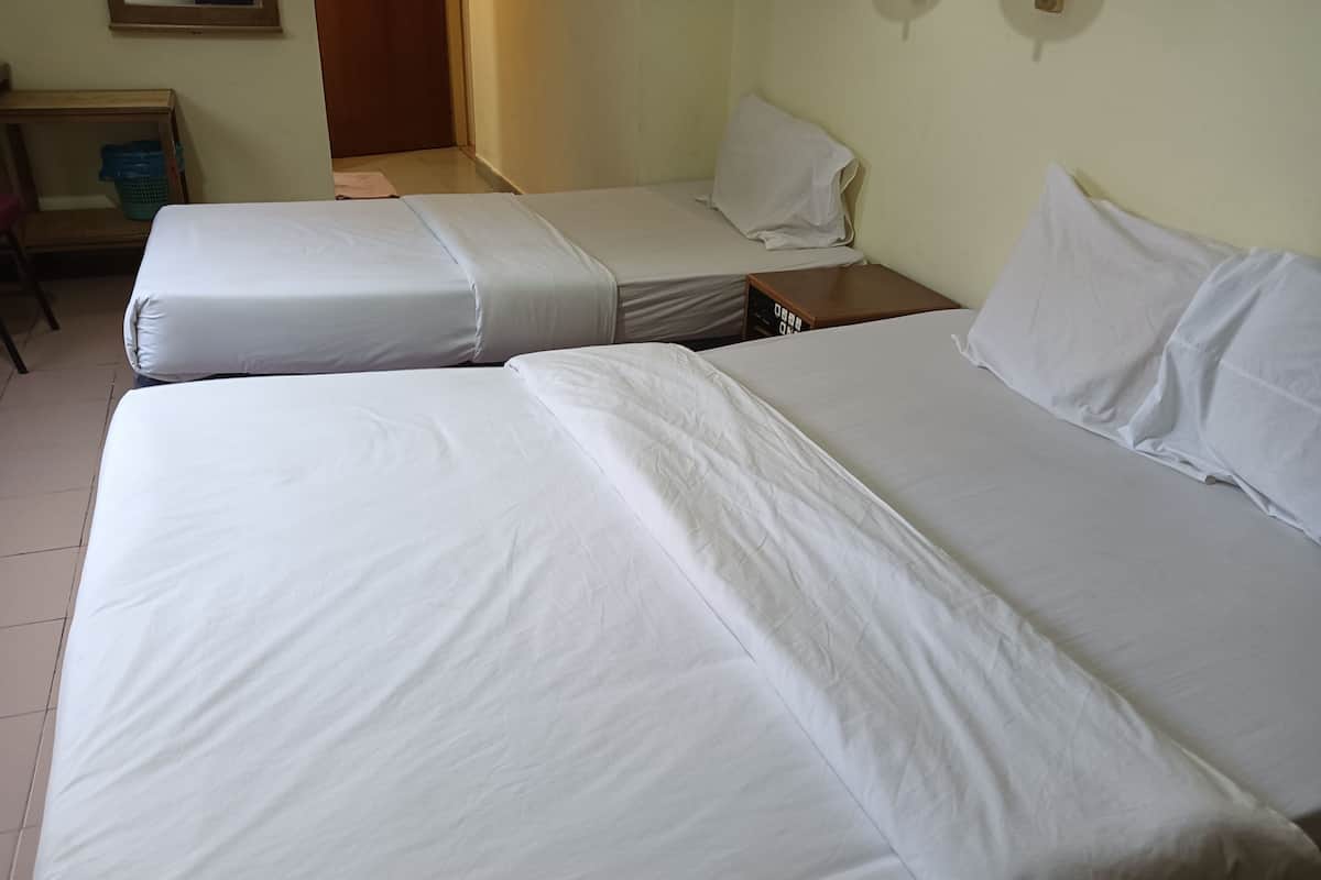 A hotel room with two single beds, a wooden nightstand, a small table, and a blue basket.