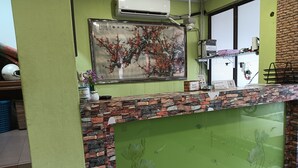 A reception desk with a stone facade, a framed artwork above it, and a green decorative panel with floral designs. - Hotel O Wawasan Inn (Sarikei)