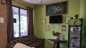 A room with a sofa, a small table with a vase of flowers, a television mounted on the wall, and a refrigerator. - Hotel O Wawasan Inn (Sarikei)