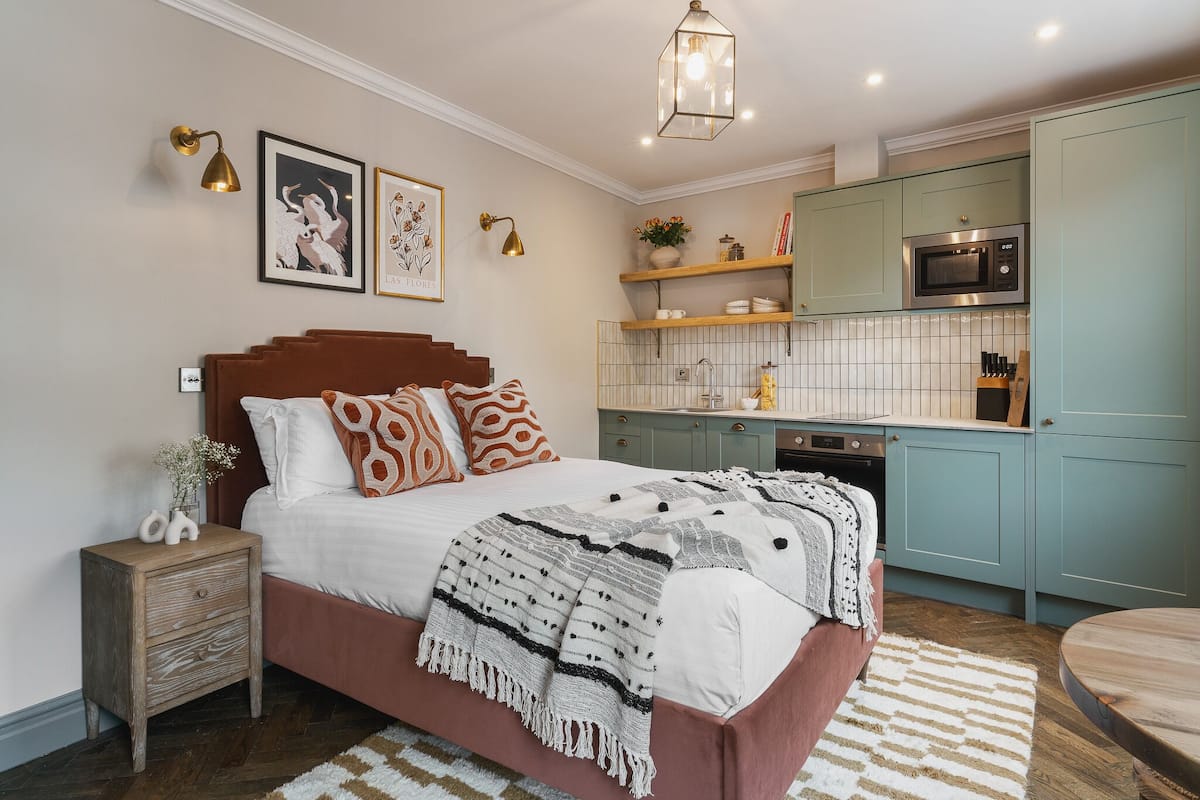 A bedroom with a bed, bedside table, and a nightstand with a lamp.