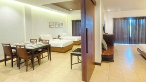 A hotel room with a dining area, a bed, a sofa, and a TV. - RB Resort (Pattaya)