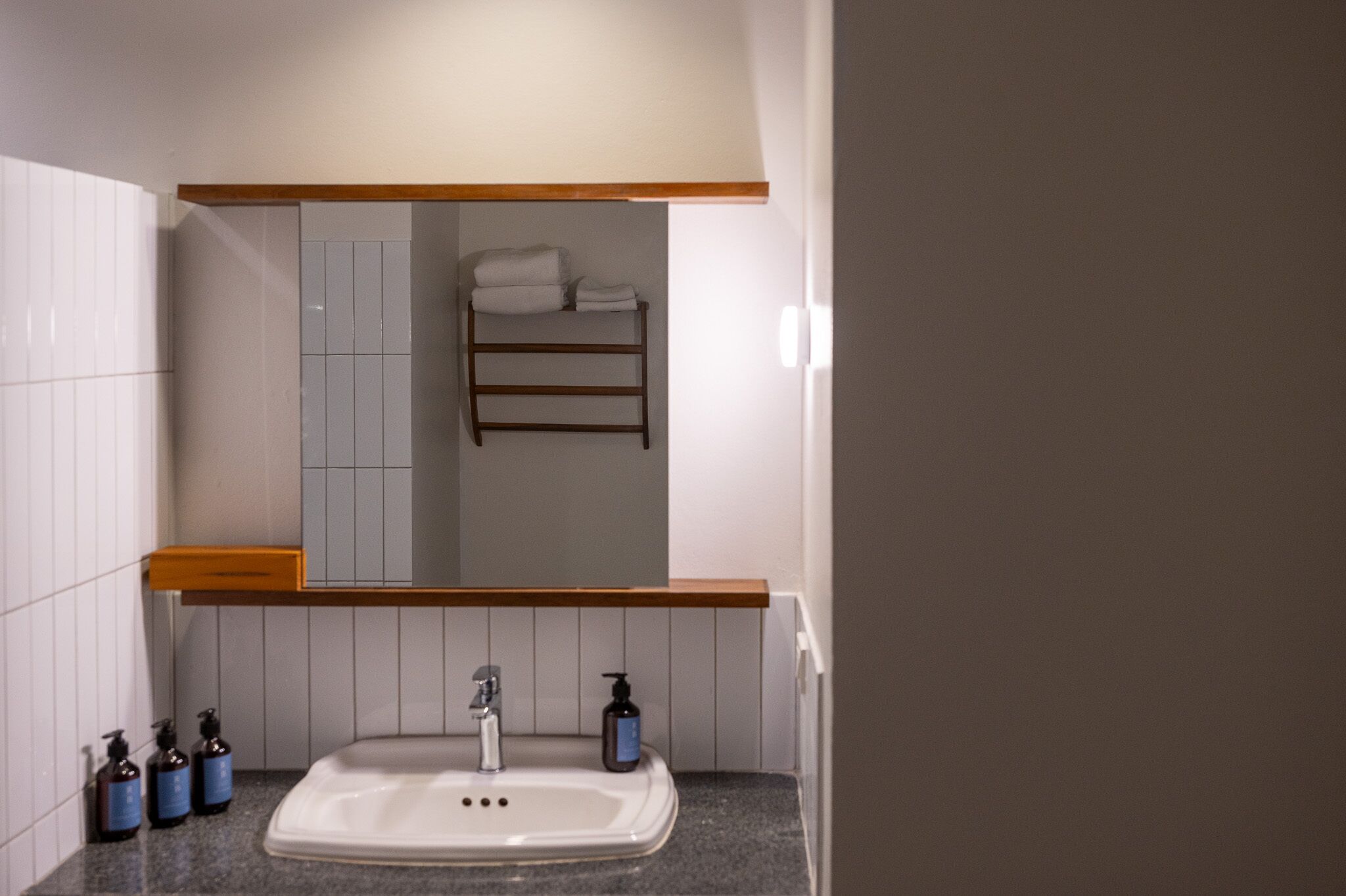 A bathroom with a sink, mirror, towel rack, and toiletries.