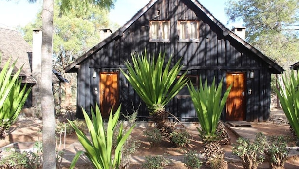 A rustic wooden cabin with a pitched roof, two front doors, and a small porch area.