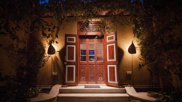 A traditional wooden entrance with a set of stairs leading up to it, surrounded by foliage. - Kumbukgaha Villa (Sigiriya)