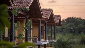 A row of traditional-style buildings with tiled roofs and columns, surrounded by greenery. - Kumbukgaha Villa (Sigiriya)