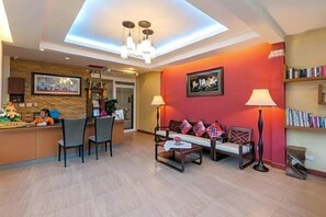 A hotel lobby with a reception desk, seating area, and a bookshelf.